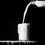 milk being poured and overflowing in glass