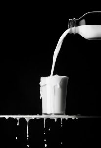 milk being poured and overflowing in glass