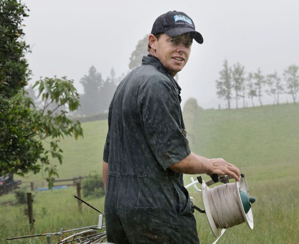 The work never stops on a dairy farm even when it is hosing down with rain Sam puts up a break fence