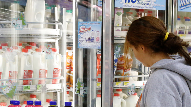 In this Dec. 4, 2013, file photo Jessica Walton, of Guthrie, Okla., reaches for a container of milk at a grocery store in Edmond, Okla. On Tuesday, Nov. 12, 2019, Dean Foods, the nation's largest milk processor, filed for Chapter 11 bankruptcy protection and said it may sell the company off to the Dairy Farmers of America.