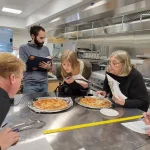 Cheese testers lean in to inspect pizzas at the University of Wisconsin's Center for Dairy Research in Madison. Maayan Silver/WUWM